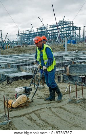 Tobolsk, Russia - July 15. 2016: Sibur company. Construction of plant on processing of hydrocarbonic raw materials. Builder worker at sand ground compaction with vibration plate compactor machine
