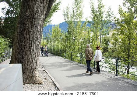 Italian People And Foreigner Travelers Walking Relax On Footpath At Riverside Of Passer River In Mer