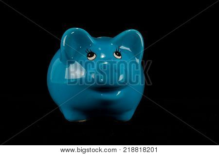 Blue piggy bank or money box isolated on a black studio background