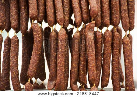 Salami and sausage hanging for sale people at organic food street market at Meran city in Merano Italy