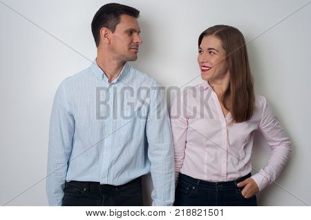 Portrait of loving middle aged couple - attractive man and woman looking at each other and smiling in casual clothes on white background