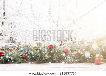 Christmas fir tree garland on wooden board on window sill over nature snowing tree park background with copy space.