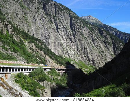 Scenic stony road tunnel in swiss Alps in SWITZERLAND near Andermatt town with alpine rocky mountains range landscape scenery with clear blue sky in 2017 warm sunny summer day, Europe on July.