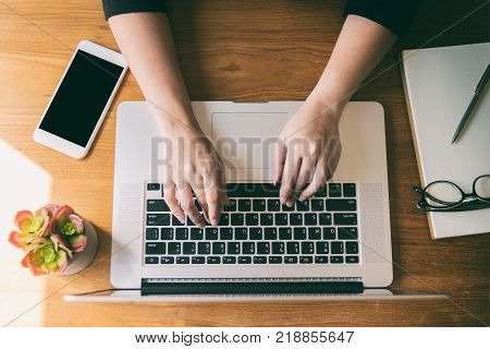 Woman using laptop in coffee shop,smartphone on table.business,accounting concept.