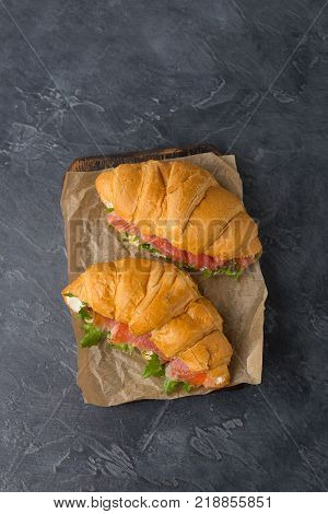 Delicious home made croissants with smoked salmon and glass of orange juice on a black background. Tasty snack. Have a nice day card.