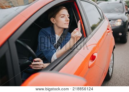 A woman feels stress on the road. Shows the fact in the window. Big Traffic jams. Business woman is late for work.