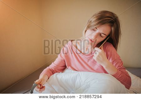 Sleepy young woman waking up with alarm. She overslept to work.