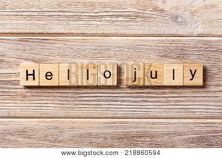 hello july word written on wood block. hello july text on table concept.