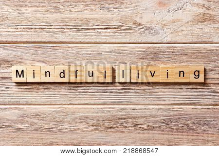mindful living word written on wood block. mindful living text on table concept.