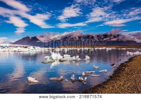The ice floes and cirrocumulus clouds of lagoon Jokulsarlon, Iceland.  Cirrocumulus magically reflected in the smooth water of the lagoon. The concept of northern extreme tourism