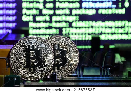 The digital process of cryptocurrency mining by using the GPUs. Bitcoins and video card on a working display and mining screen