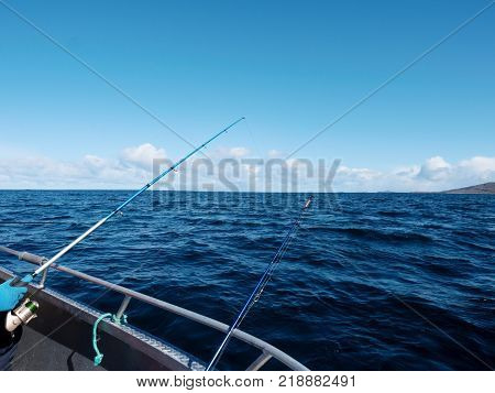 Fishing boat with fishing rods floating in open sea. Background beautiful sky. Sport sea fishing