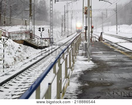 Electric railway and a train arriving winter scene station platform in the foreground