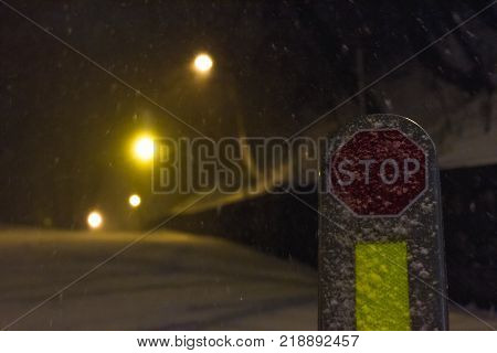 Red stop sign in winter snowy conditions. Nigt city blizzzard