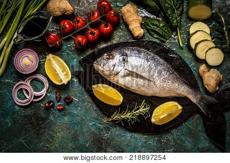 Dorada fish with vegetables lemon spices and greens on a blue background
