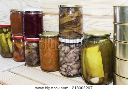 Storage shelves in pantry with homemade canned preserved fruits and vegetables.