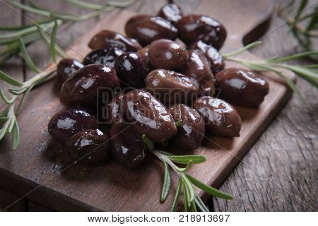 Cured, pickled or brined olive fruit on wooden table