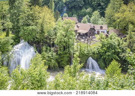 Croatian Village Of Rastoke By A River Canyon With Wooden Houses In A Green Landscape With Trees And