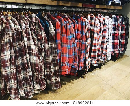 Men's checkered shirts on hangers in the store. Inside the clothing store at Department Store.