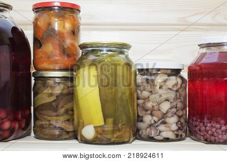 Storage shelves in pantry with homemade canned preserved fruits and vegetables.