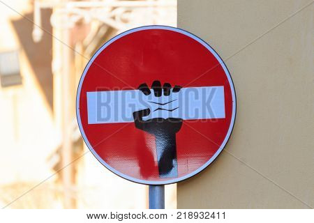 Road sign with an hand that break out the signal street art metropolitan art
