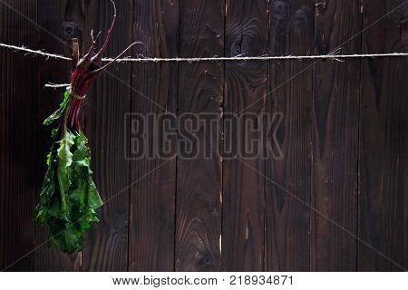 Fresh betroots hanging on string.Wooden background.Concept hanging herbs.free space