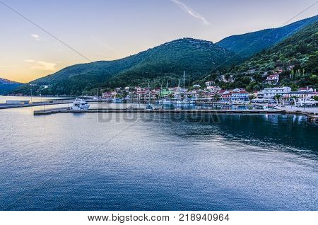Panoramic view from the sea of the port of Sami with its moorings the port facilities and back the mountains illuminated by the sunset sun Kefalonia