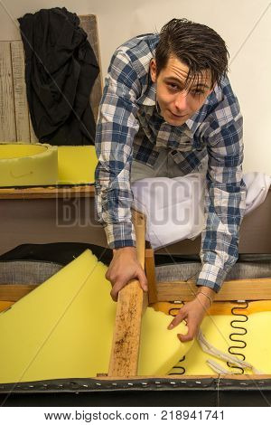 upholsterer padding a sofa with open framing in the upholsterer shop