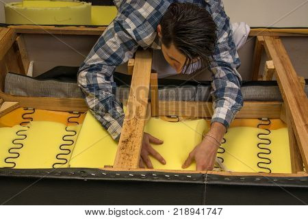 upholsterer padding a sofa with open framing in the upholsterer shop