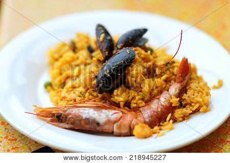 delicious rice dish with mussels and royal prawns on white plate