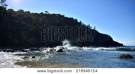 A wave crashing against rocks at the beach