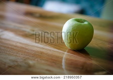 Fresh green apple on wooden table in kitchen