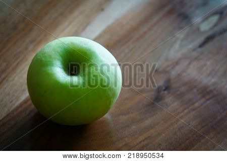 Fresh green apple on wooden table in kitchen