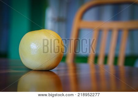 Fresh grapefruit on wooden table with wooden chair in background
