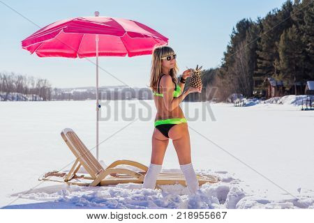 Novokuznetsk, Kemerovo region, Russia - 23 Feb, 2017 : White beaches of Siberia is an enterteiment activity where people playing beach games dressed in bikini in winter. Woman in bikini with pineapple