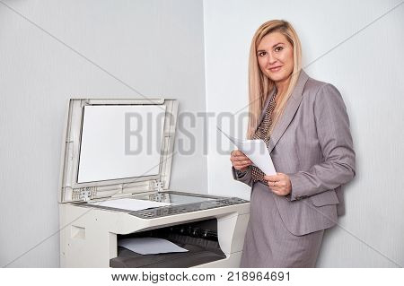 Businesswoman working on a copy machine at the office.