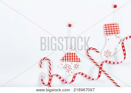 Christmas holiday composition. Festive creative red pattern, xmas handmade decor holiday with ribbon, candy canes, gift, christmas tree and decorations on white background. Flat lay, top view
