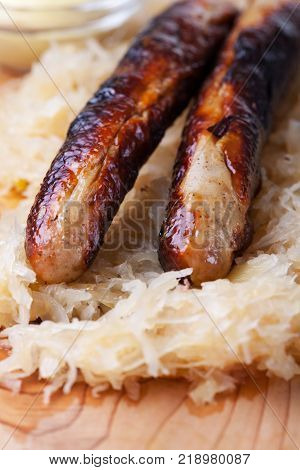closeup of grilled sausages with sauerkraut on wood