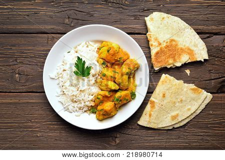 Delicious chicken curry with rice on wooden background. Top view flat lay
