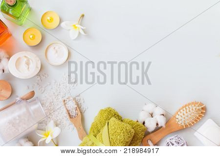 Wellness spa setting with natural soap, cream, candles and towels on a white wooden background with copy space