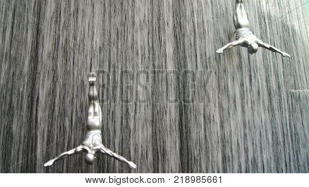 DUBAI, UNITED ARAB EMIRATES - MARCH 31st, 2014: Famous Waterfall in Dubai Mall world's largest shopping mall - 30m in diameter and 24 meters high with art fiberglass sculptures of human divers