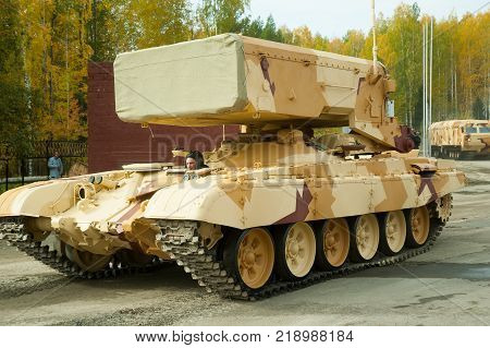 Nizhniy Tagil, Russia - September 26. 2013: Visitors examine military equipment on exhibition range. TOS-1A system fighting vehicle SAolncepek in motion. Russia Arms Expo-2013 exhibition