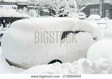 Car covered with first snow. Car buried under the snow and frozen. Bank of snow in winter