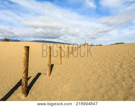 Sand in the Dunes of Maspalomas, a small desert on Gran Canaria, Spain. Sand and sky, and a wooden fence marking the forbidden area of the bird nature reserve La Charca.