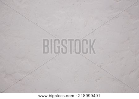 White and Gray Dirty Plaster Wall, With Falling Off Flakes Of Paint. Rough Surface. Old Weathered Painted Grey Background Texture. Vintage Timber Background. Peeled Plaster Brickwall