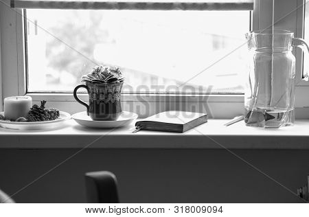 Flower Violet In A Pot, A Carafe With A Foda And A Diary For Planning The Day On The Windowsill.blac