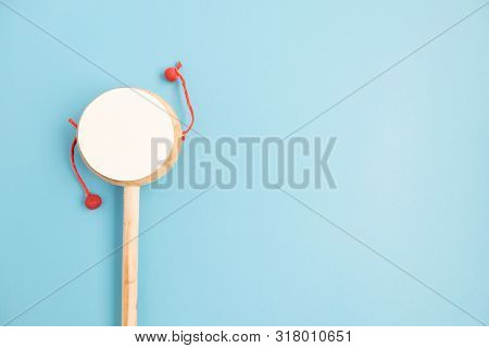 Top View Of Kids Sound Making Toy Damaruga On Blue Background.