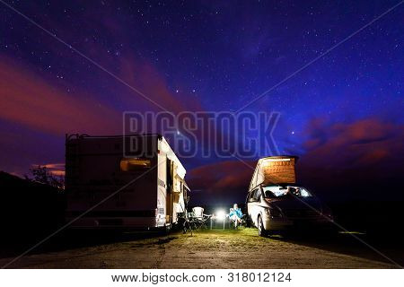 Campervans Are Parked On A Beach At Night Under Stars.
