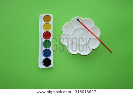 Brush, Paint, Palette To Mix On A Green Background. Watercolor And Colored Objects For School And Cr