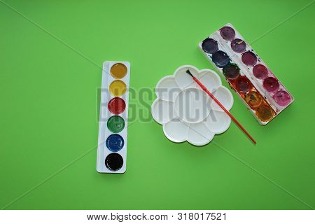 Brush, Paint, Palette To Mix On A Green Background. Watercolor And Colored Objects For School And Cr